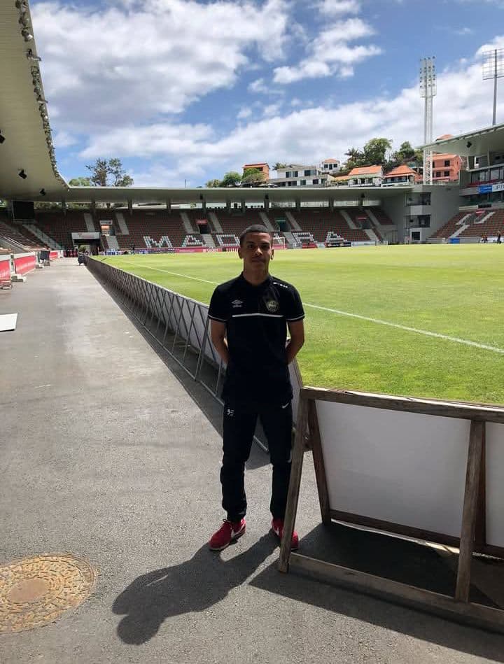Jeune homme en tenue de sport noire devant le terrain de football à Madère.